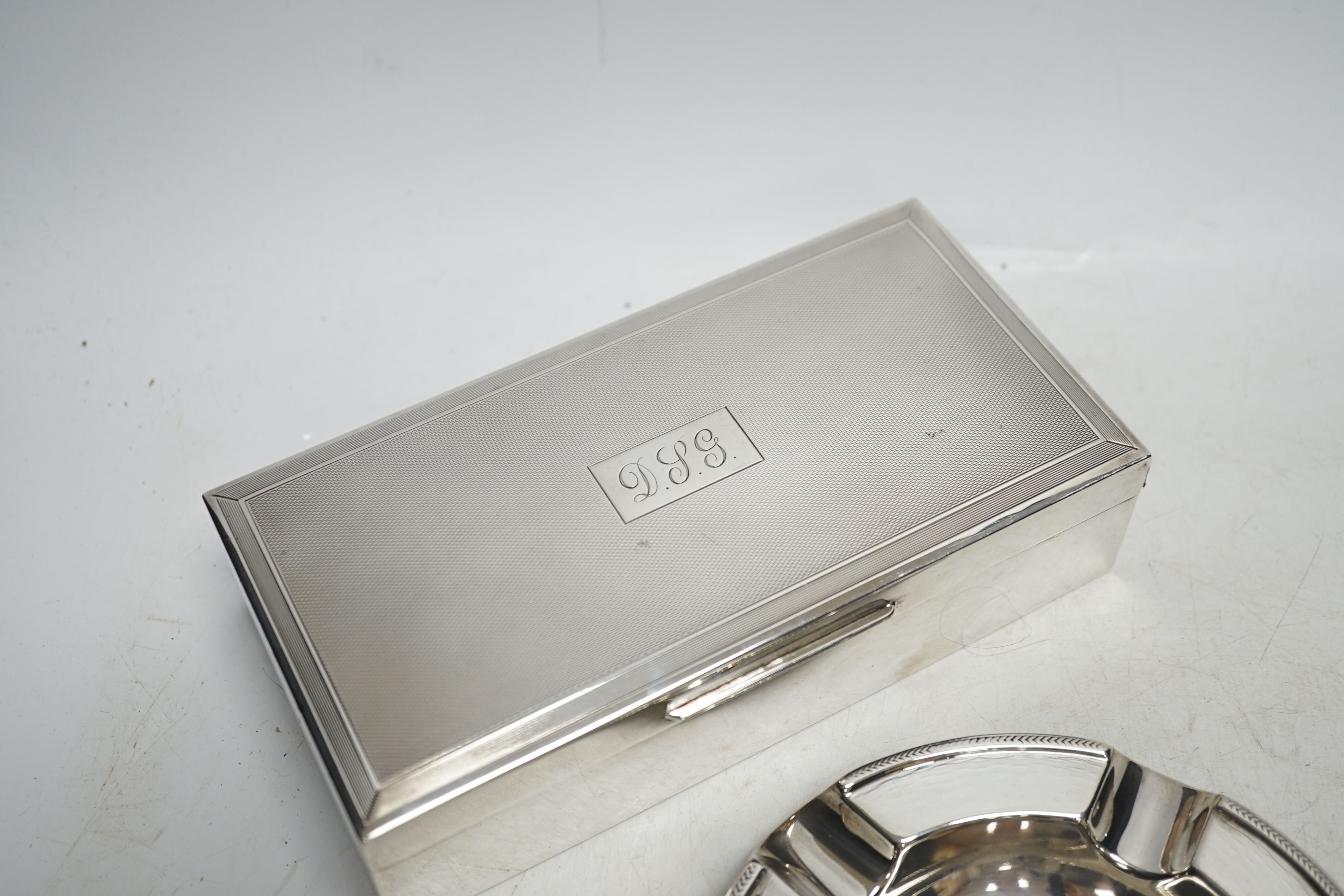 A 1960's engine-turned silver mounted rectangular cigarette box, 17.8cm and a silver ashtray. Condition - fair